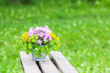 Güzel bir buket kır çiçeği ahşap bankta yaz mevsiminde kırsal alanda doğa arka planında.