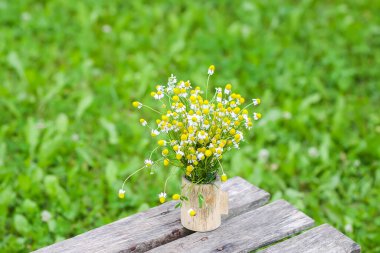 Güzel bir buket kır çiçeği ahşap bankta yaz mevsiminde kırsal alanda doğa arka planında.