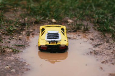 Yağmurdan sonra kirli bir su birikintisinde plastik oyuncak araba.