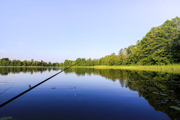 Spinning with reel on evening lake background.