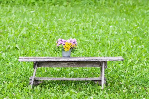 田舎の夏の自然を背景にした木製のベンチで美しい花の花束 — ストック写真