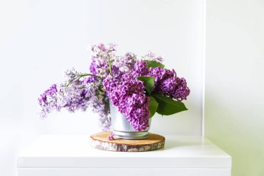 Açık arkaplanda güzel mor leylak çiçeklerinden bir buket. Yaygın şırınga bitkisi. Doğal dekor. Minimalist hafif iç kısımda ahşap kesim üzerine çiçek kompozisyonu