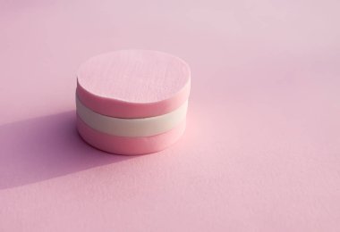 Pembe arka planda pastel renkli kozmetik süngerler.