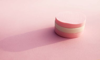 Pembe arka planda pastel renkli kozmetik süngerler.