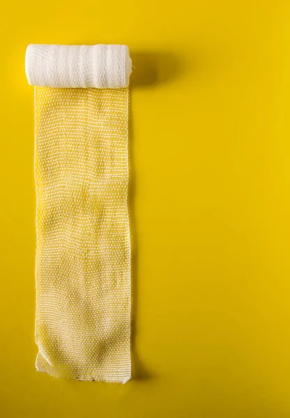 White medical bandage on yellow background close up.