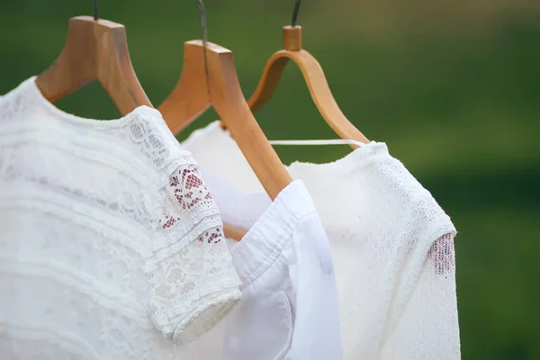 Linen dresses hanging on a wooden hangers outdoors in summer day