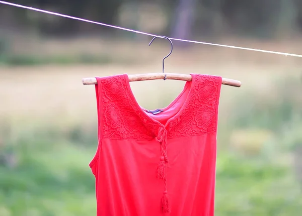 Linen red dress hanging on a hanger outdoors in summer day