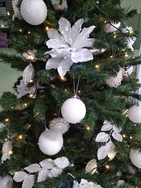 White Christmas toys on the tree in the form of balls and flowers