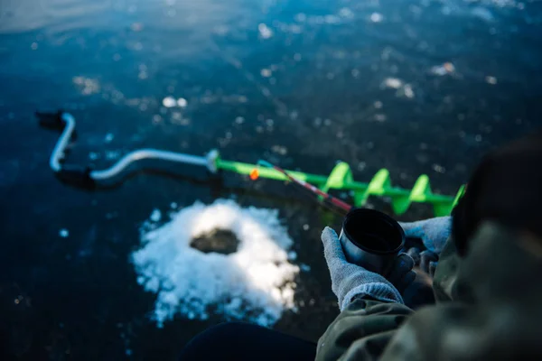 En man är fiske på isen på vintern. — Stockfoto