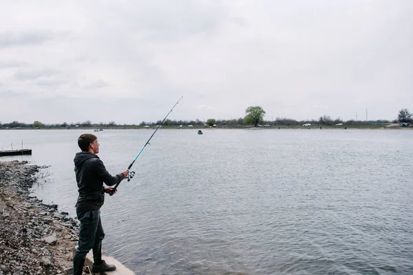 Il pescatore getta lo spinning nel fiume in una giornata di sole — Foto Stock