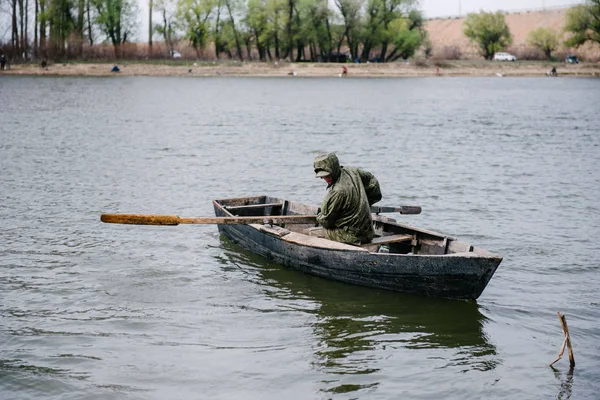 Un uomo sta remando su una barca di legno — Foto Stock