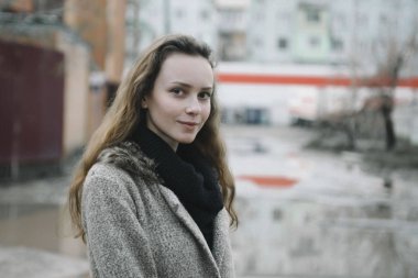 Kahverengi hırkayla sokakta poz veren genç bir kadın.