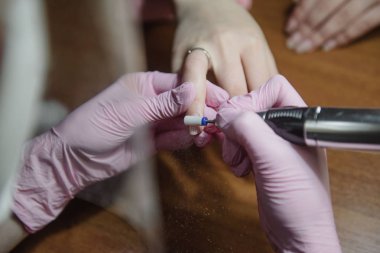 Manikürcü donanım manikür yakın çekim yapar. Hırdavat manikür yardımı ile çivi tedavisi