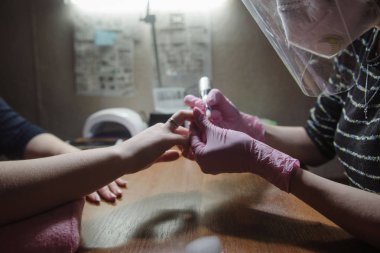 Manikürcü donanım manikür yakın çekim yapar. Hırdavat manikür yardımı ile çivi tedavisi