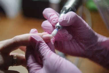 Manikürcü donanım manikür yakın çekim yapar. Hırdavat manikür yardımı ile çivi tedavisi