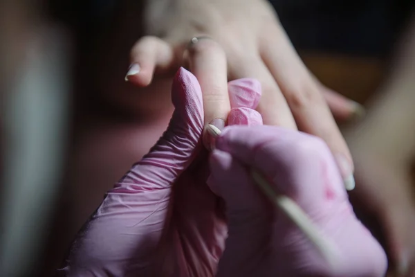 Manicura hace una manicura higiénica con la ayuda de un palo naranja de cerca —  Fotos de Stock