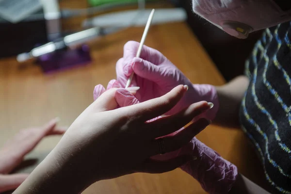 Manicura hace una manicura higiénica con la ayuda de un palo naranja de cerca —  Fotos de Stock