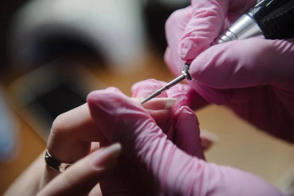 Manicurist makes hardware manicure close-up. Treatment of nails with the help of hardware manicure