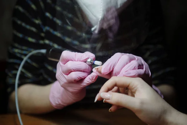 Manicurist makes hardware manicure close-up. Treatment of nails with the help of hardware manicure