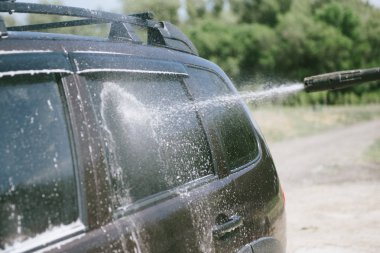 Bir adam yüksek basınçlı yıkıcı ile bir araba yıkar