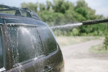 Bir adam yüksek basınçlı yıkıcı ile bir araba yıkar