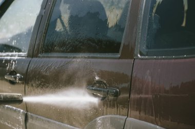 Bir adam yüksek basınçlı yıkıcı ile bir araba yıkar