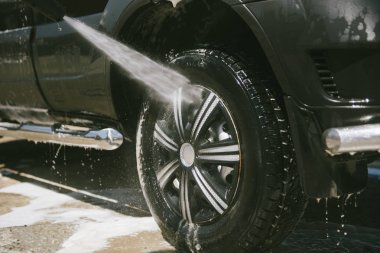 Bir adam yüksek basınçlı yıkıcı ile bir araba yıkar