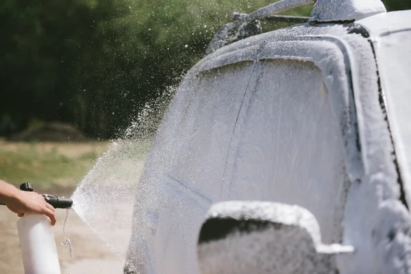 Un hombre rocía un agente de limpieza lavando una alta presión en el coche — Foto de Stock