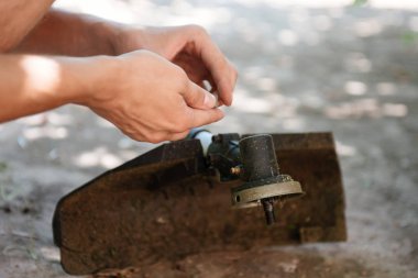 Bir adam bir düzeltici onarır. Bir adam yakın çekim bir çim biçme makinesi onarır.