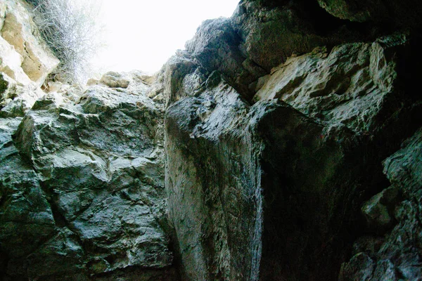 Dark cave with a bright daylight spot of exit. Natural cave opening. Entrance to the karst cave in a mountain.