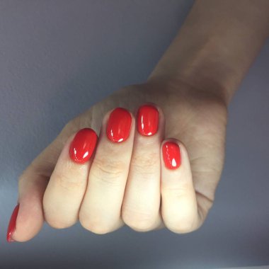 Gri arka planda şık kırmızı manikür ile Kadın eller