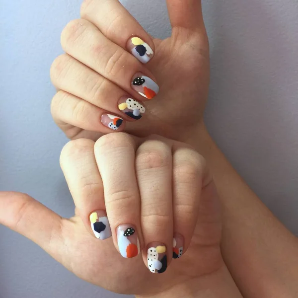 Manicure de cores diferentes em pregos. Manicura feminina na mão sobre fundo azul — Fotografia de Stock