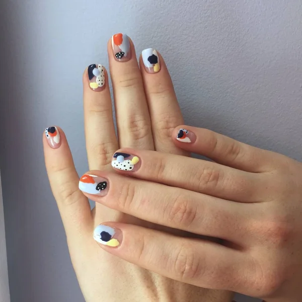 Manicure de cores diferentes em pregos. Manicura feminina na mão sobre fundo azul — Fotografia de Stock