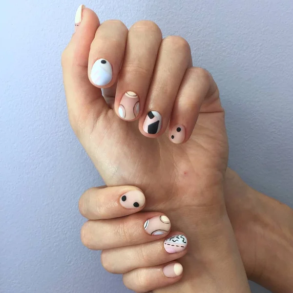 Manicura de diferentes colores en las uñas. Manicura femenina en la mano sobre fondo azul — Foto de Stock