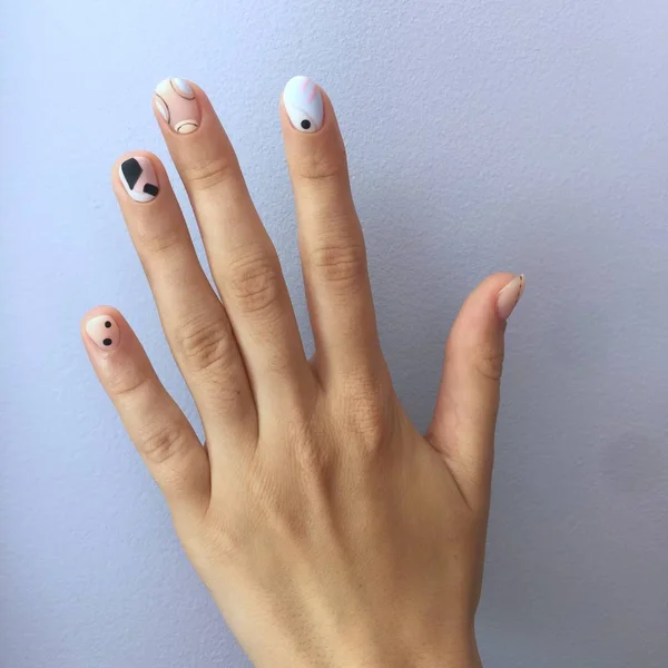 Manicure de cores diferentes em pregos. Manicura feminina na mão sobre fundo azul — Fotografia de Stock