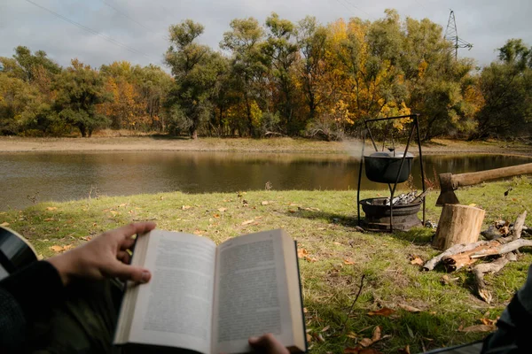 Pensativo joven turista sentado y leyendo libro en tienda de campaña turística en el bosque —  Fotos de Stock