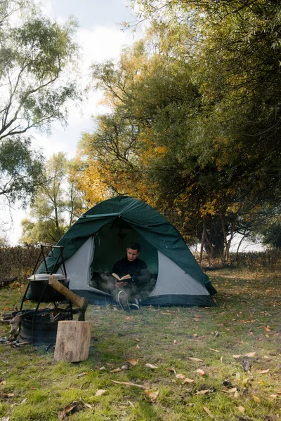 富有思想的年轻人旅游坐着看书旅游帐篷中森林 — 图库照片