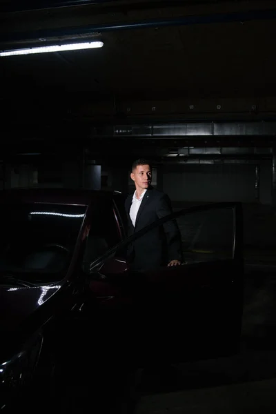 Ypung man in zwart pak opent zijn auto deur — Stockfoto