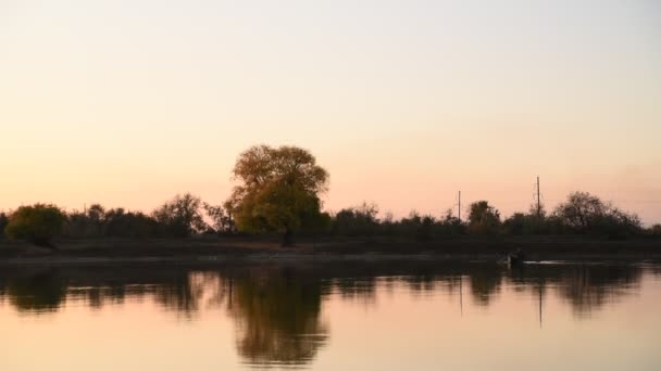 夕方の日没をかむ中で漁師のシルエット回転釣りリール 川での夜の釣り 釣り中の美しい夕日 — ストック動画