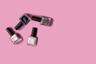 Pembe arka planda renkli tırnak törpüsü olan şişeler. Manikür konsepti. Manikür aksesuarları..