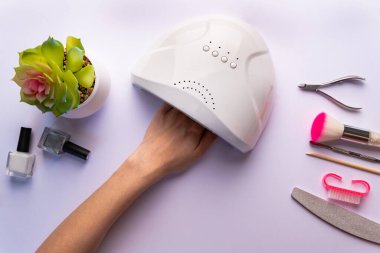 Ultraviyole lambada çivi kurutmak. Bir kadın çivi kurutmak için ultraviyole lamba kullanıyor. UV lambalı kadın el, üst görünüm