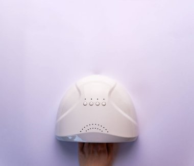 Ultraviyole lambada çivi kurutmak. Bir kadın çivi kurutmak için ultraviyole lamba kullanıyor. UV lambalı kadın el, üst görünüm