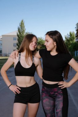 Spor giyimli iki kız stadyumda poz veriyor. Spor stadyumunda iki kız arkadaşın portresi..