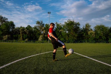 Genç erkek futbolcu futbol sahasında top çeviriyor. Stadyumda ayaklarıyla top hokkabazlığı yapıyor. Futbol sporu konsepti.