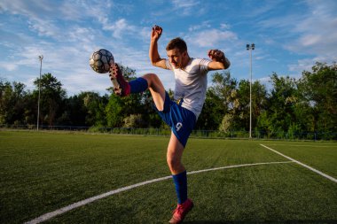 Genç erkek futbolcu futbol sahasında top çeviriyor. Stadyumda ayaklarıyla top hokkabazlığı yapıyor. Futbol sporu konsepti.