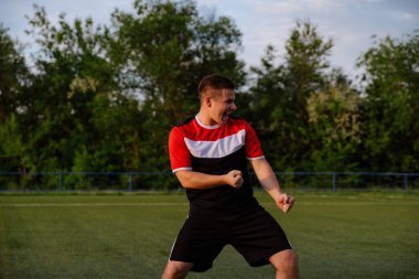 Futbol oyuncusu futbol stadyumunda gol kutluyor. Mutlu futbolcu bir futbol stadyumunda zaferi kutluyor.