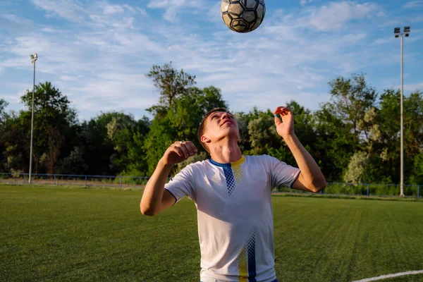 Young male soccer player juggles a ball on a soccer field.sport, football and people - soccer player playing and juggling ball using header technique on field.Football sports concept