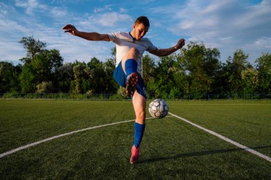 Genç erkek futbolcu futbol sahasında top çeviriyor. Stadyumda ayaklarıyla top hokkabazlığı yapıyor. Futbol sporu konsepti.