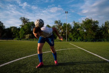 Genç erkek futbolcu futbol sahasında top çeviriyor. Stadyumda ayaklarıyla top hokkabazlığı yapıyor. Futbol sporu konsepti.