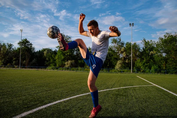Genç erkek futbolcu futbol sahasında top çeviriyor. Stadyumda ayaklarıyla top hokkabazlığı yapıyor. Futbol sporu konsepti.
